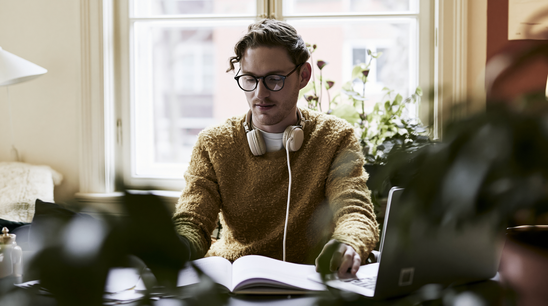 Learner studying at home with laptop and book